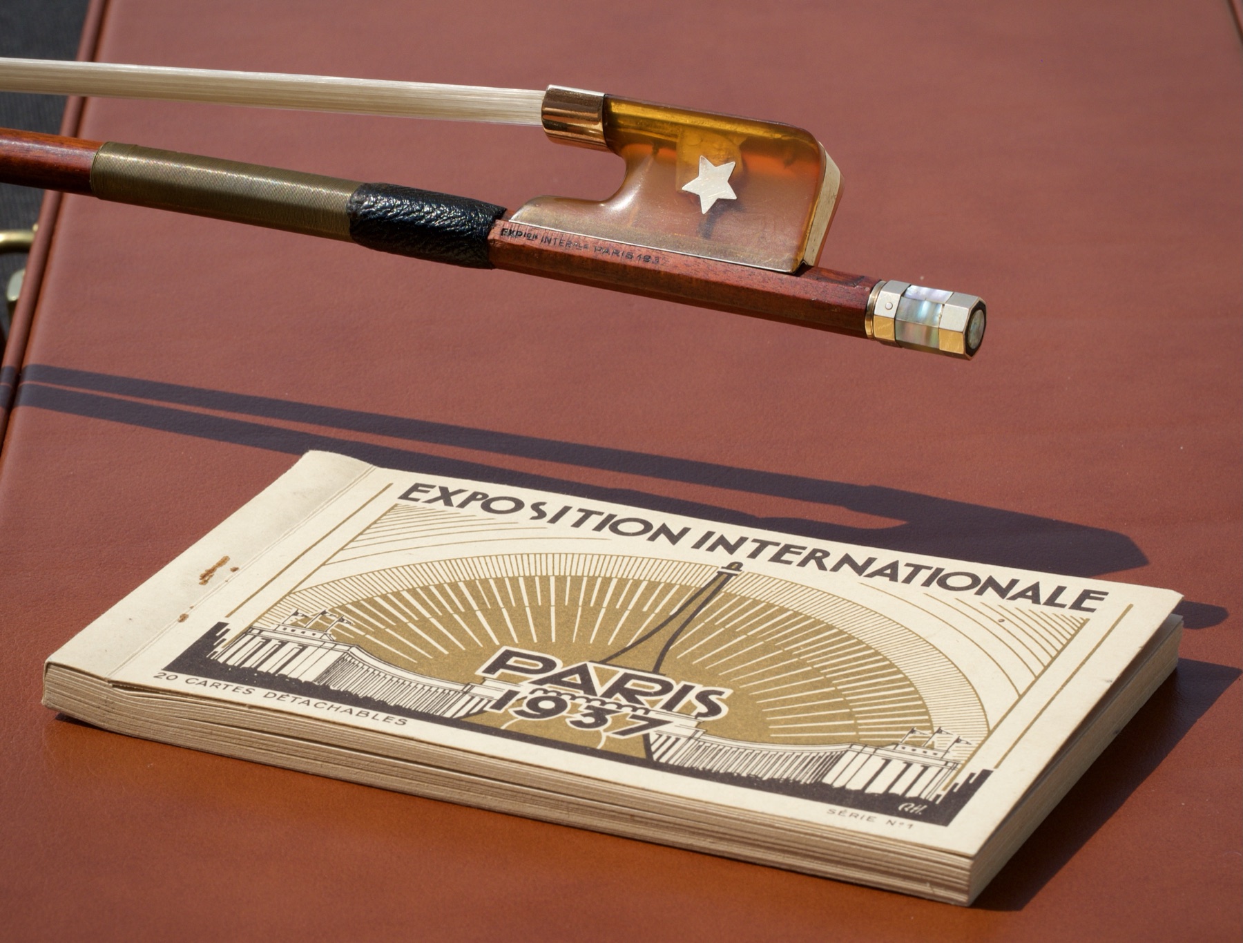 Cello bow by E.A. Ouchard, ex André Navarra, beside a 1937 Paris Exposition catalogue